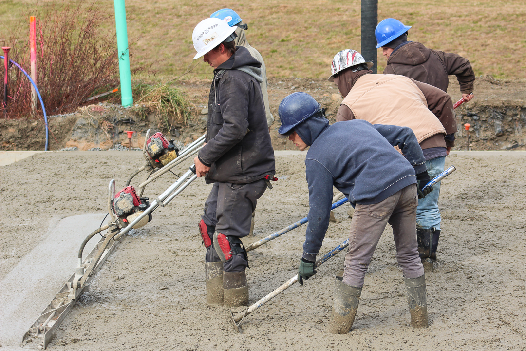 Excavation crew leveling and finishing concrete pour at a residential construction site by MDi Excavation.