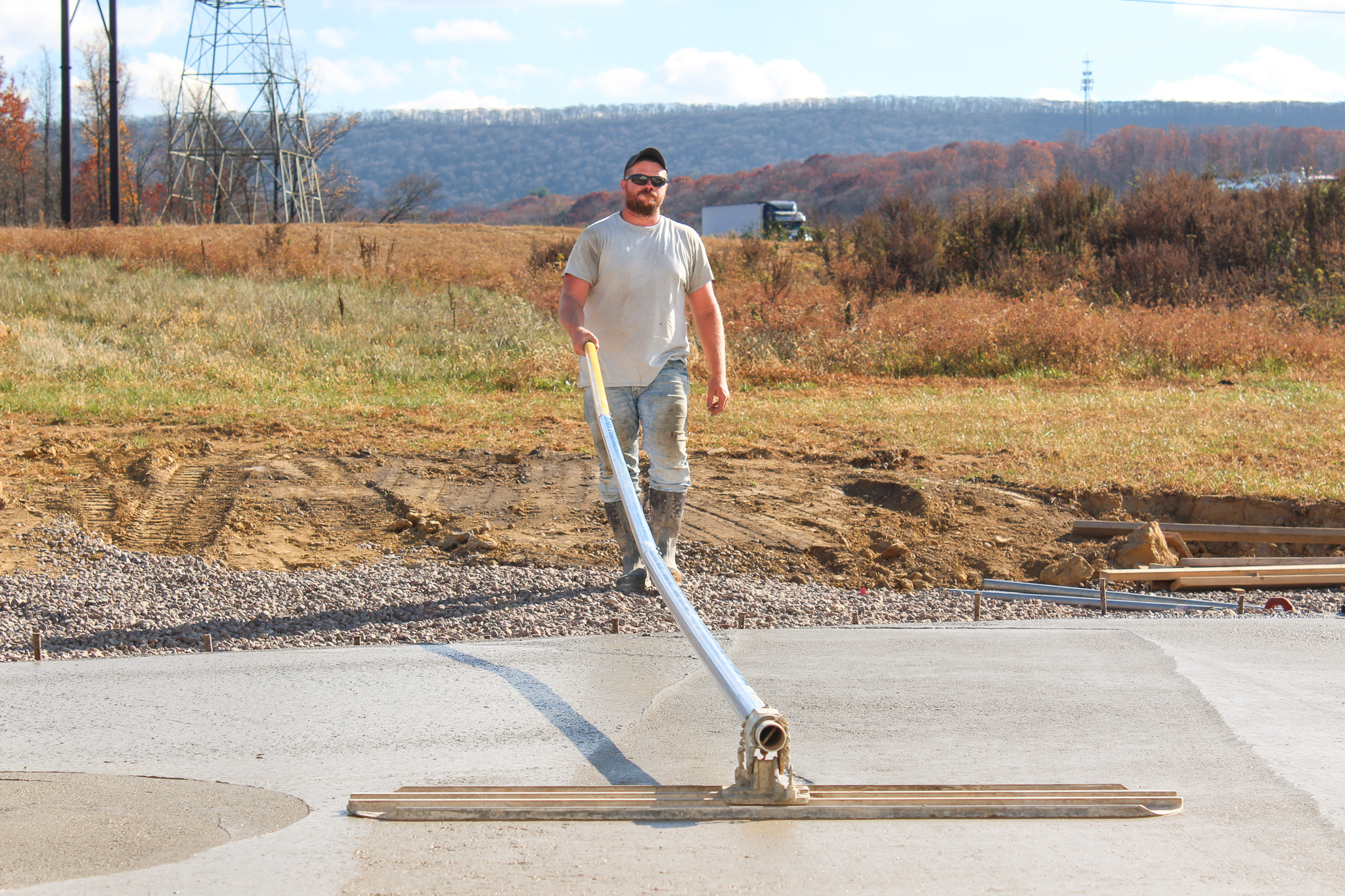 Worker applying concrete sealer to driveway.
